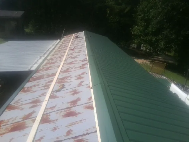 Old rusted panels beside newly installed green metal roofing — Wind Damage Roof Repair by Roofing Brothers in Tarpon Springs