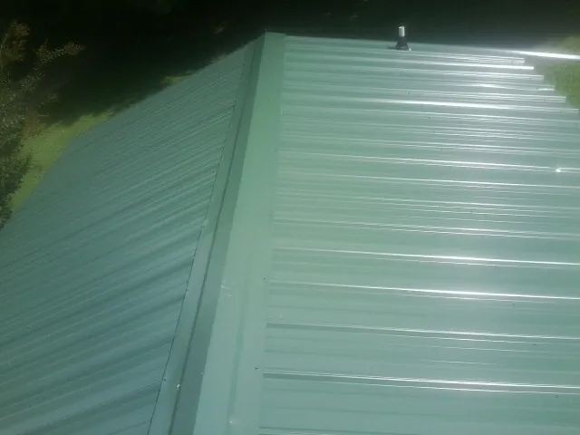 New green metal panels meeting at the ridge of a roof — Flat Roof Repair work by our crew in Tarpon Springs
