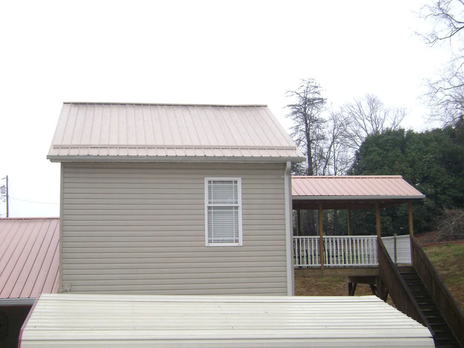 Tan metal roofs on a two story addition and attached porch, from a Roof Replacement job in Tarpon Springs