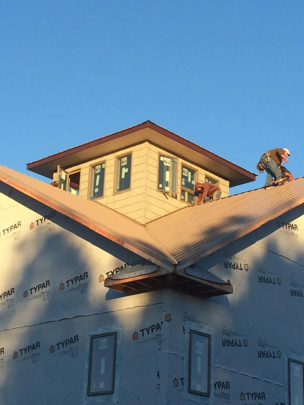 Roofers working around a rooftop cupola on a new metal roof at sunset — Roof Waterproofing in Tarpon Springs by Roofing Brothers